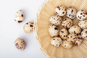 quail eggs in a shell in a basket on a light background
