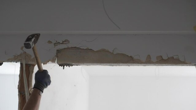 Man hitting a wall trying to remove a lintel during apartment remodeling