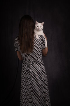 studio portrait of a woman in a polkadot dress with white cat on shoulder