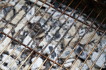 Glowing charcoal and grill grate. Dirty barbecue rust after cooking.