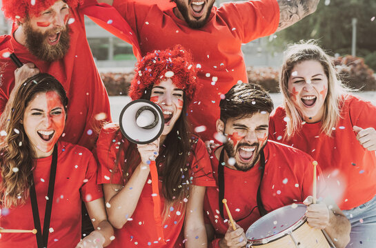 Football fans having fun supporting club on soccer match event at stadium