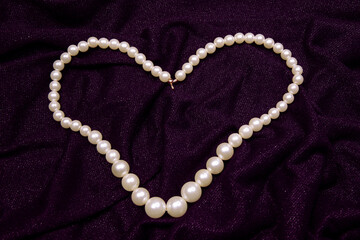 Valentine's Day image with white perl necklace in heart shape on a purple background