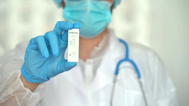 Hand in protective glove holds rapid antigen test for covid-19. Quick swab method to test Coronavirus. PCR