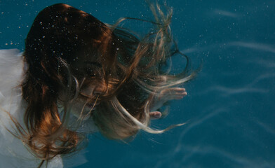 Portrait of beautiful woman in bridal dress underwater.