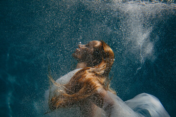 Portrait of beautiful woman in bridal dress underwater. © Stanislav