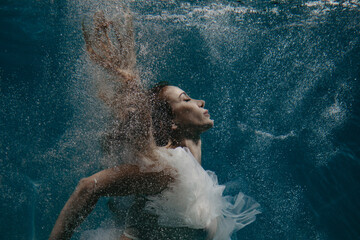 Portrait of beautiful woman in bridal dress underwater.