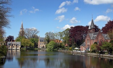 El lago Minnewater en Minnewaterpark, Brujas, Bélgica. A orillas del lago se encuentra el Invernadero y al fondo la torre de la Iglesia de Nuestra Señora.