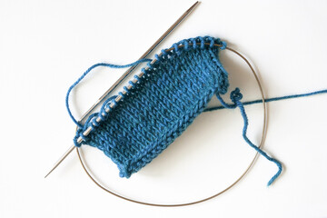 Stockinette stitch knitting on circular needles, blue turquoise knit stitches isolated on white...