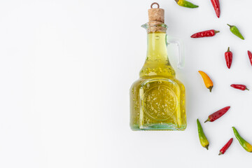 Chili peppers and olive oil bottle on white wooden background, top view