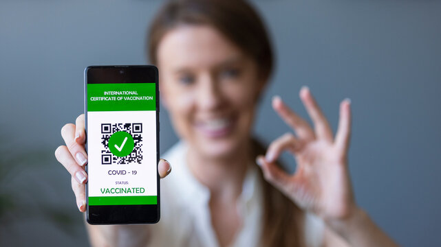 Close up of view hands women holding smartphone display on app mobile vaccinated COVID-19 or coronavirus certificate, immunity vaccine passport, new normal travel of tourist concept.
