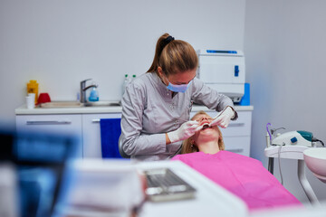 Female dentist examining the teeth of a young woman