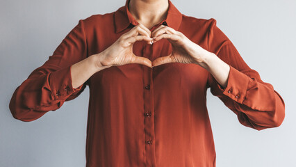 Crop close up of happy woman feel grateful thankful show heart sign spread love and care. Smiling biracial female volunteer make hand gesture support ill sick people patients. - Powered by Adobe