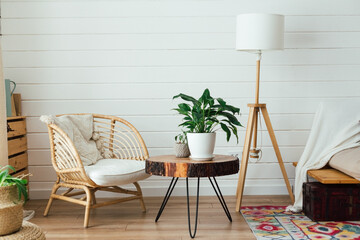 Rattan armchair and floor lamp in living room interior with plants. Cozy interior in boho style. Real photo - 485538284