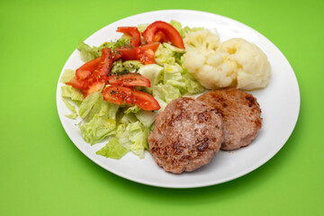 ground meat with fresh salad and boiled cauliflower on white plate