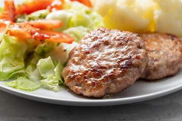 Fried ground meat with fresh salad and boiled cauliflower on white plate