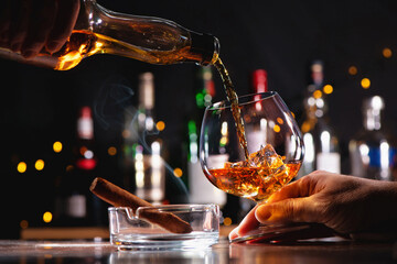 Pouring a whiskey in a glass on bar counter - obrazy, fototapety, plakaty
