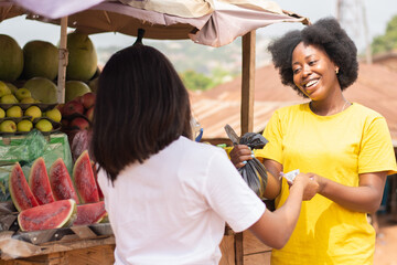african lady paying for fruits in a market