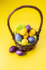 Easter eggs in a basket on a yellow-purple background. Multicolored eggs. Easter. Photo