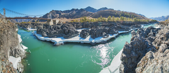 Bridge across the Katun River in the Altai Mountains, sunny day in early spring, panoramic view