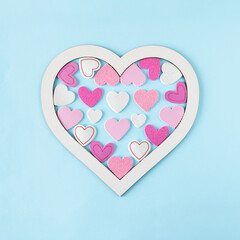 White heart shaped frame filled with smaller pink hearts. Minimal concept of Valentine's Day on a...