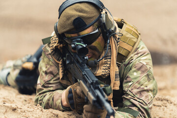 Focused soldier at ground level stance aiming using target scoop . High quality photo