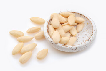 White bowl of peeled or blanched almonds on white background.  Shallow depth of field