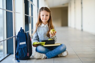 schoolgirl holding lunch box and apple going to eat