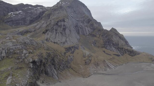 Aerial view of steep mountains at the Bunes beach, cloudy Lofoten, Norway - ascending, drone shot