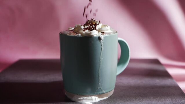 Chocolate sprinkles on hot chocolate drink on pink background