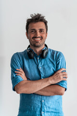 Formal business male portrait. A confident successful casual businessman or manager stands in front of a white background, arms crossed, looking directly at the camera and smiling friendly. High