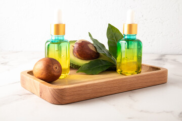 two cosmetic bottles with a dropper pipette made of colored glass with a cosmetic, oil or serum with avocado for daily skin care.