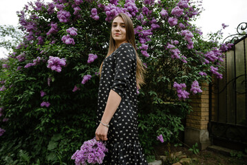 portrait of a beautiful girl in lilac flowers in the garden. spring time.