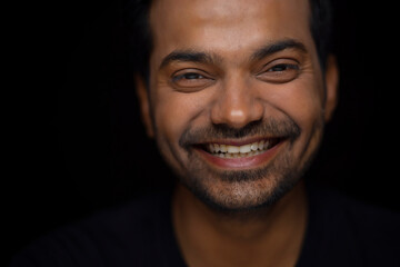 Obraz premium Close-up portrait of a happy young man against dark background