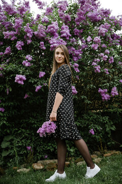 portrait of a beautiful girl in lilac flowers in the garden. spring time.