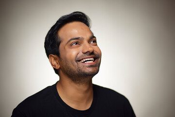Obraz premium Portrait of happy young man looking above with smile