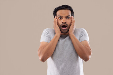 Portrait of a surprised young man with mouth opened and hands on cheek