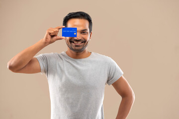 Happy young man showing credit card in front of camera