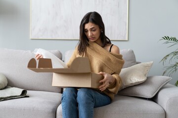 Angry confused woman unpacking parcel, wrong or broken online store order. Bad delivery service