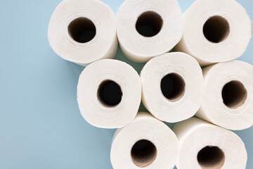 Fresh new white toilet paper rolls on blue background. Personal hygiene and health issues concept. Top view, copy space