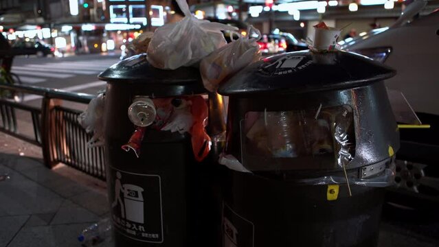 Two black bins full of rubbish on the city street. Pile of garbage waste on the footpath. Many pollution trash and plastic overflowing container and dirty the floor