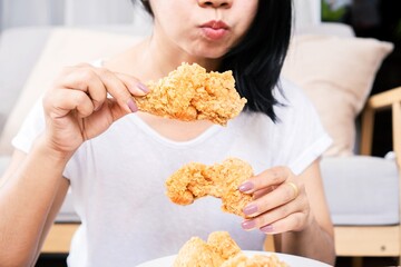 Asian woman over eating oily, junk food hand holding fried chicken closeup