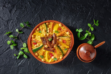 Couscous with meat and vegetables, festive Moroccan food, overhead flat lay shot on a black slate...