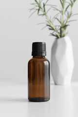 Amber glass essential oil bottle mockup with a rosemary on the white table.