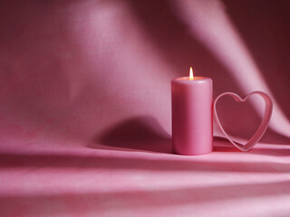 Romantic pink candle and love heart on pink background 