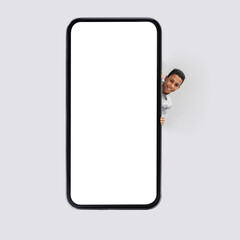 Black Boy Posing Near Big Smartphone Blank Screen, Gray Background