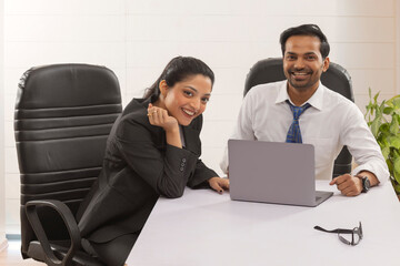 Happy business couple looking at camera with smile while working
