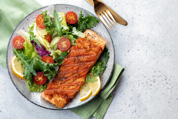 Grilled salmon fish fillet and fresh green lettuce vegetable tomato salad