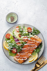 Grilled salmon fish fillet and fresh green lettuce vegetable tomato salad