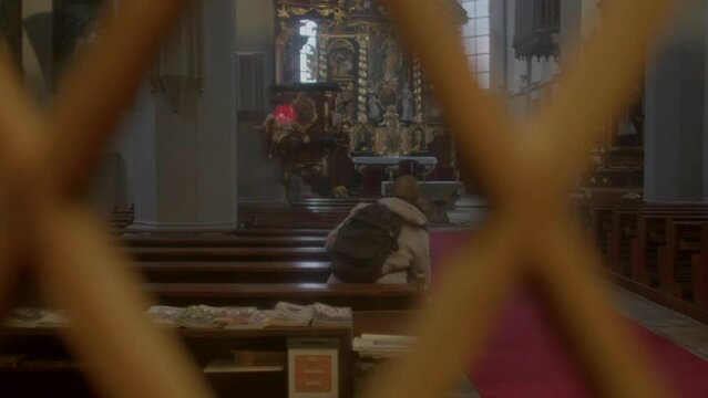 A man is sitting on a bench. He finishes his prayer and leaves the building. The end of a religious ritual.