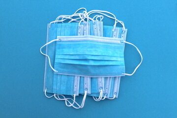 A pile of medical masks lie on a blue background.